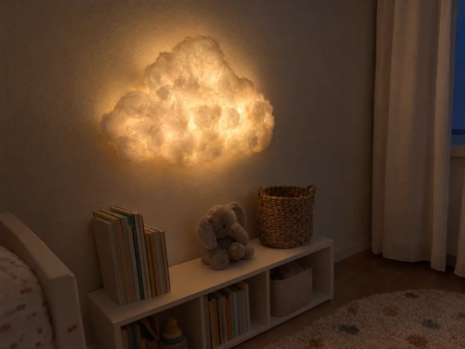 Nube de pared plana hecha con guata, encendida con luz cálida en un cuarto infantil