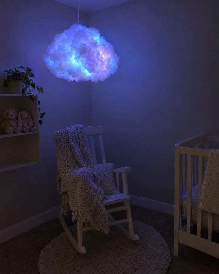 Nube colgante encendida en celeste y lila en el rincón de un cuarto de bebé, sobre una mecedora